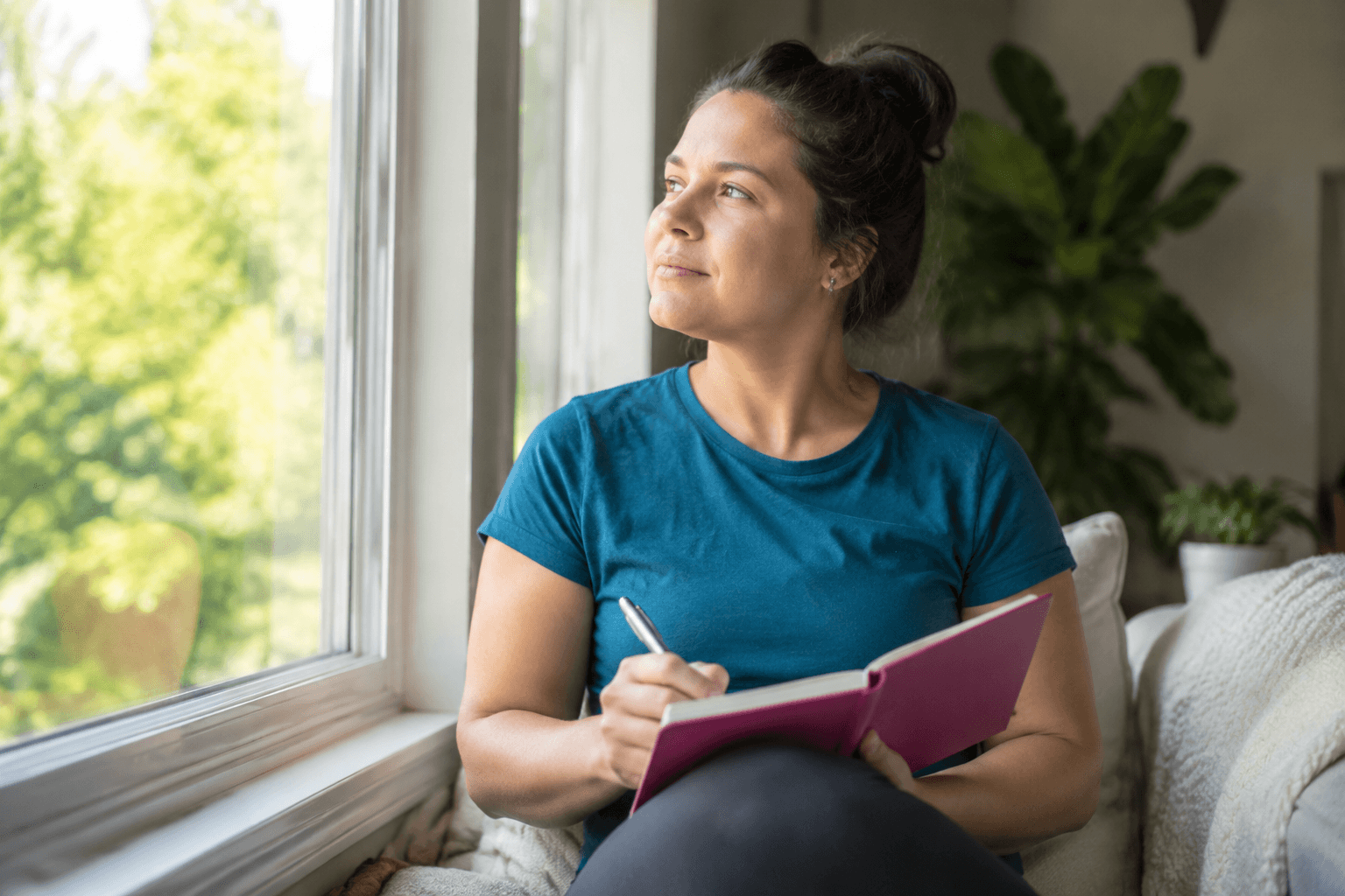 Woman journaling by window, representing hypnosis for changing self-sabotaging patterns
